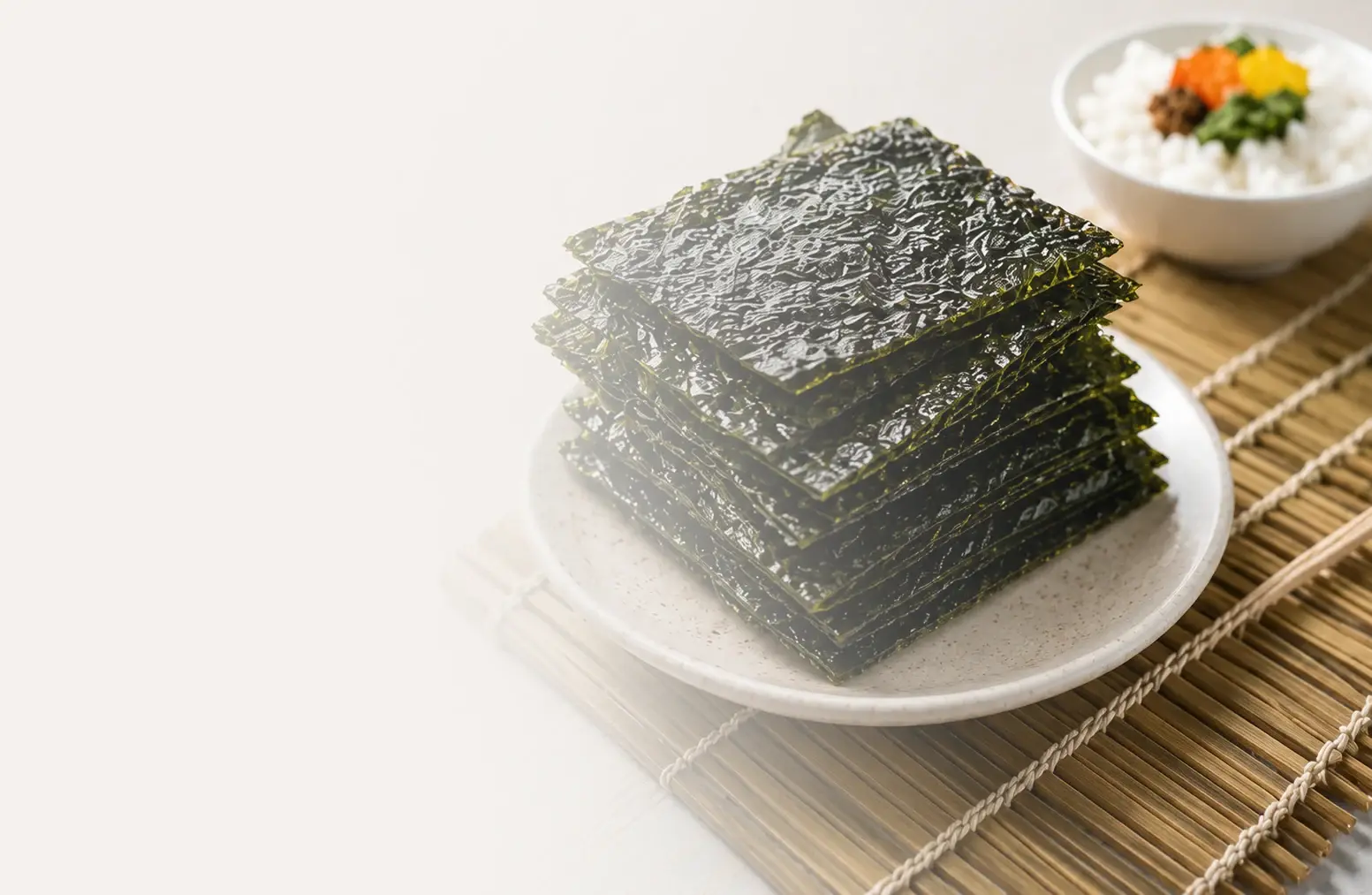 Stacked sheets of Norigo nori beside a bowl of rice